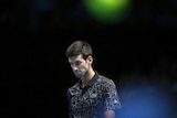 Novak Djokovic walks across the court at the ATP World Tour Finals tennis match against John Isner.
