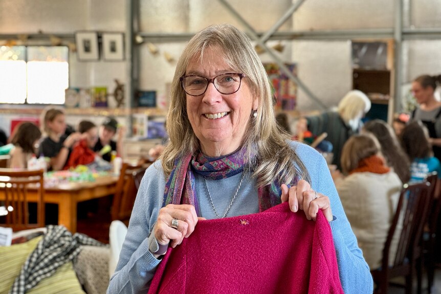 Woman holds jumper with a small patch of darning