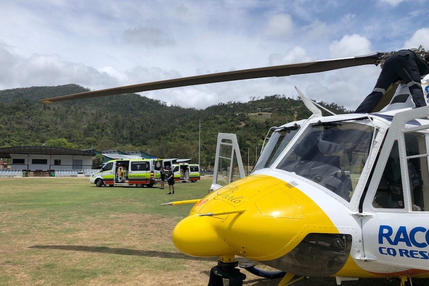 A rescue helicopter on a oval. Behind it sits two ambulances.