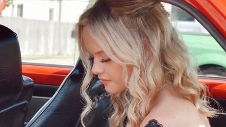 A young woman with blonde curls gets out of a car