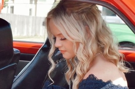 A young woman with blonde curls gets out of a car
