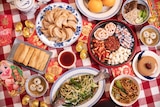 8 lucky Lunar New Year foods including dumplings, spring rolls, oranges, whole fish, year cake and sweet rice dumplings.