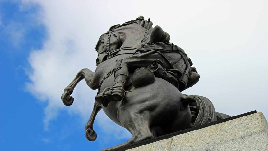 An iron statue of a horse against a blue sky.