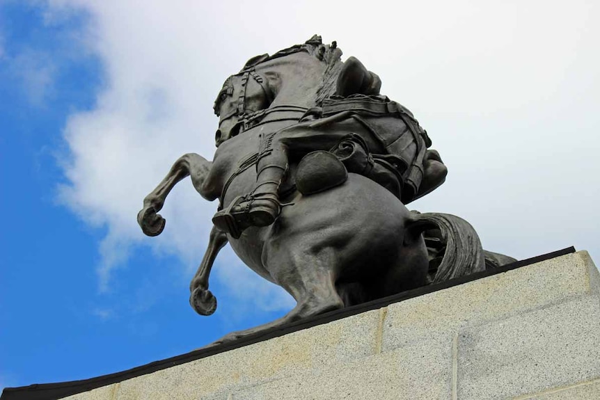 An iron statue of a horse against a blue sky.