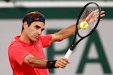 A male tennis player plays a single-fisted backhand volley at the French Open in Paris.