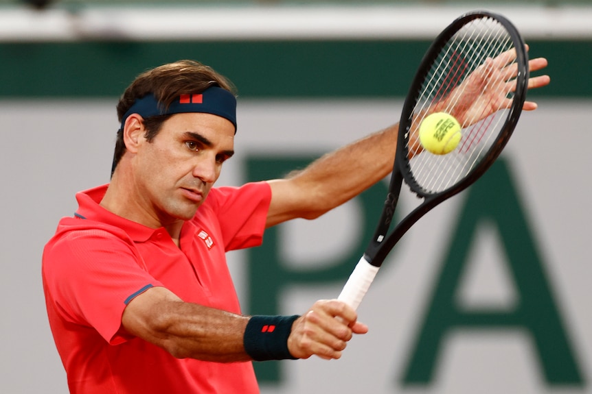 A male tennis player plays a single-fisted backhand volley at the French Open in Paris.