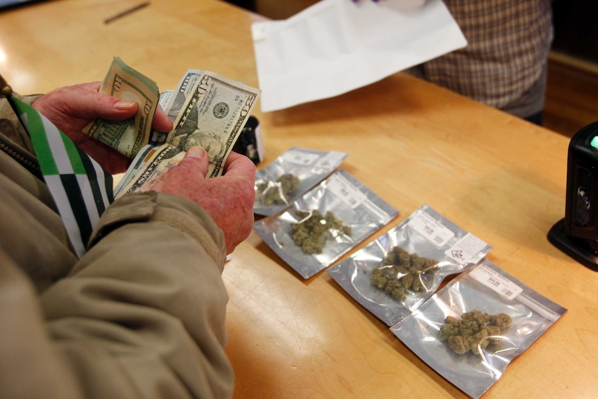 A close-up photo shows someone counting through money to buy marijuana.