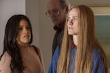 Worried-looking Gina Rodriguez standing next to Evan Rachel Woods in doorway, looking at her, with Richard Jenkins behind.