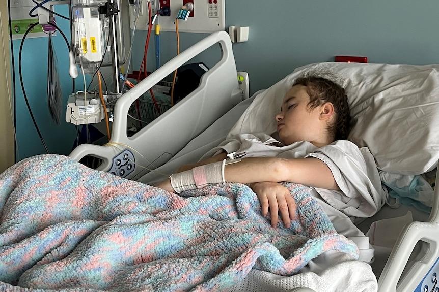 A teenager girl lays in a hospital bed asleep. 