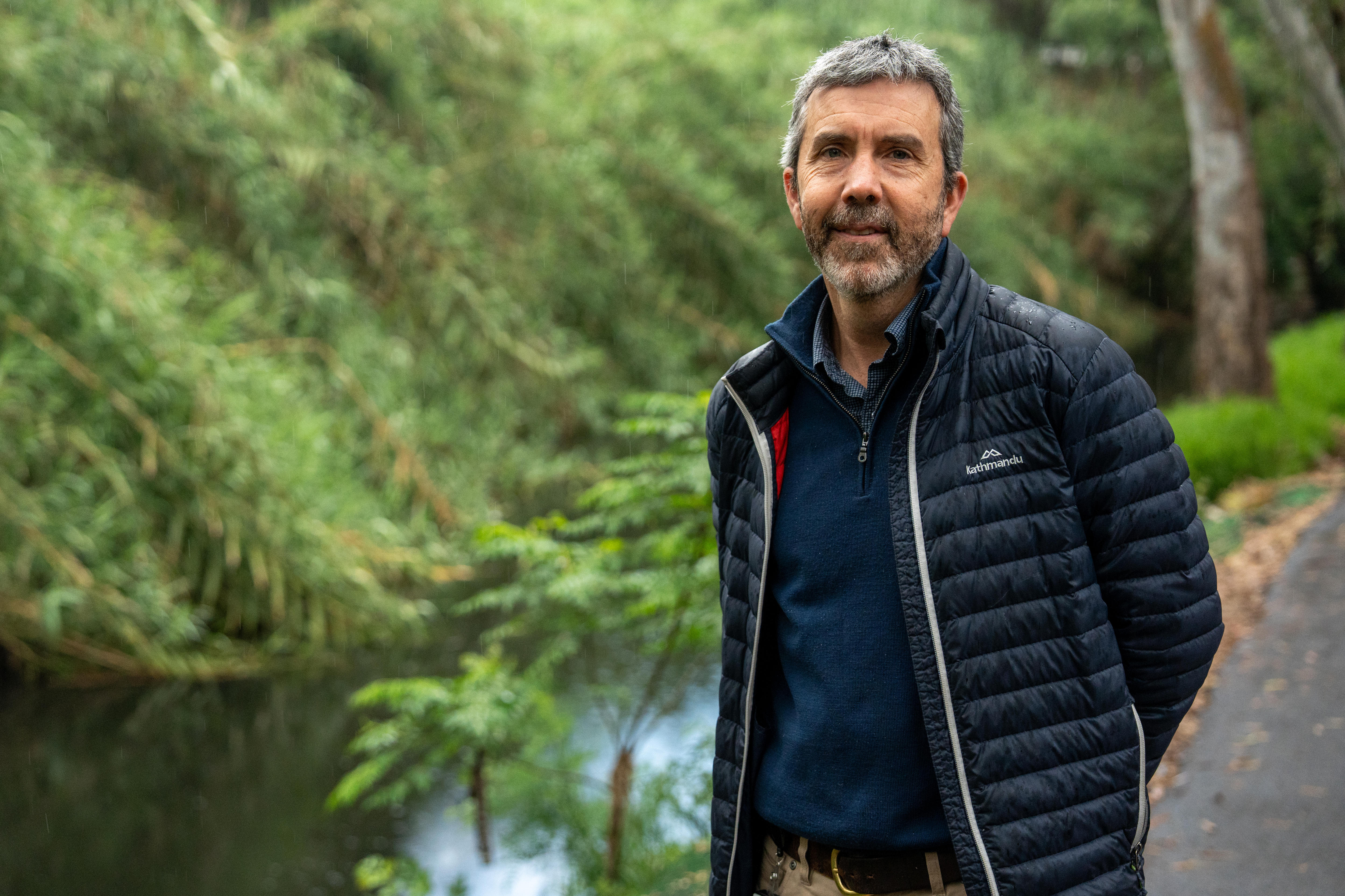 A man in a puffer jacket next to a river.