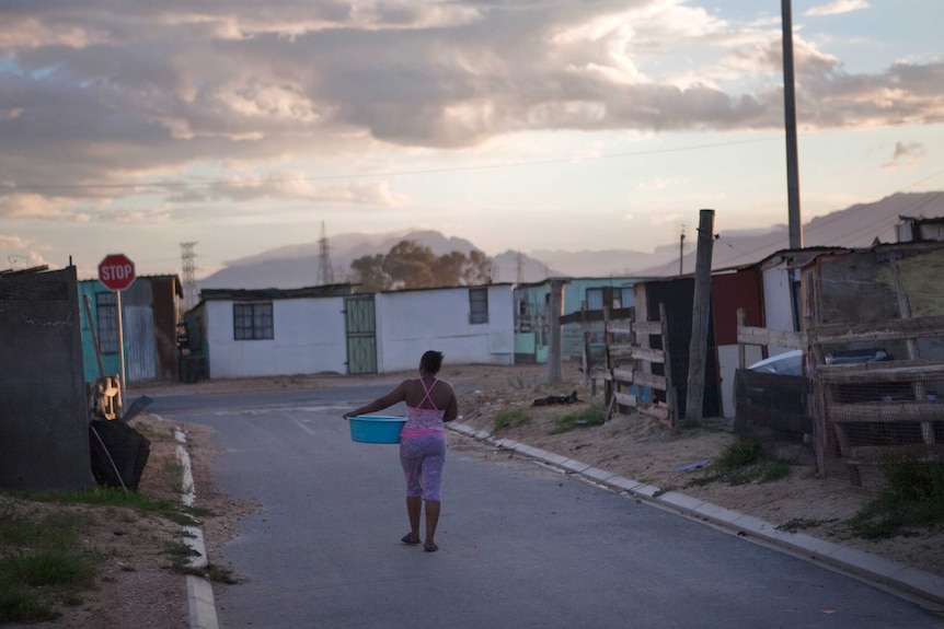 Township resident walking down the street with a washing basin