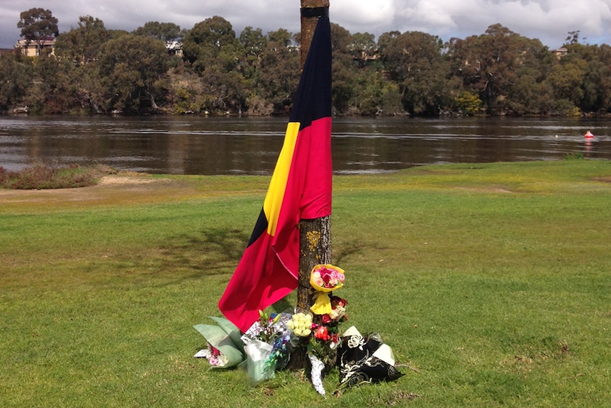 An Aboriginal flag with flowers around it.