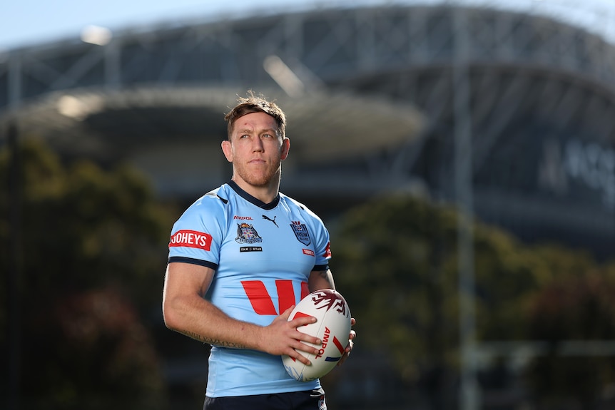 A man poses in a New South Wales jersey before a State of Origin game