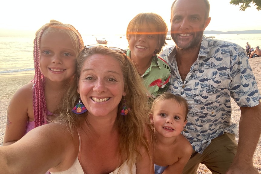Victoria Vanstone poses for a selfie on a beach with her partner and three kids, they regularly take device free holidays. 