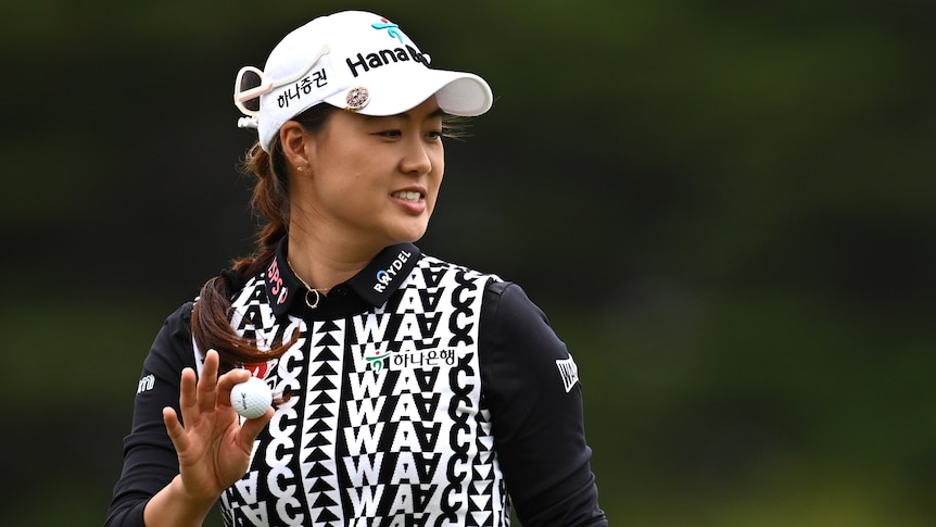 An Australian female golfer holds a golf ball in her right hand at the Australian Open.