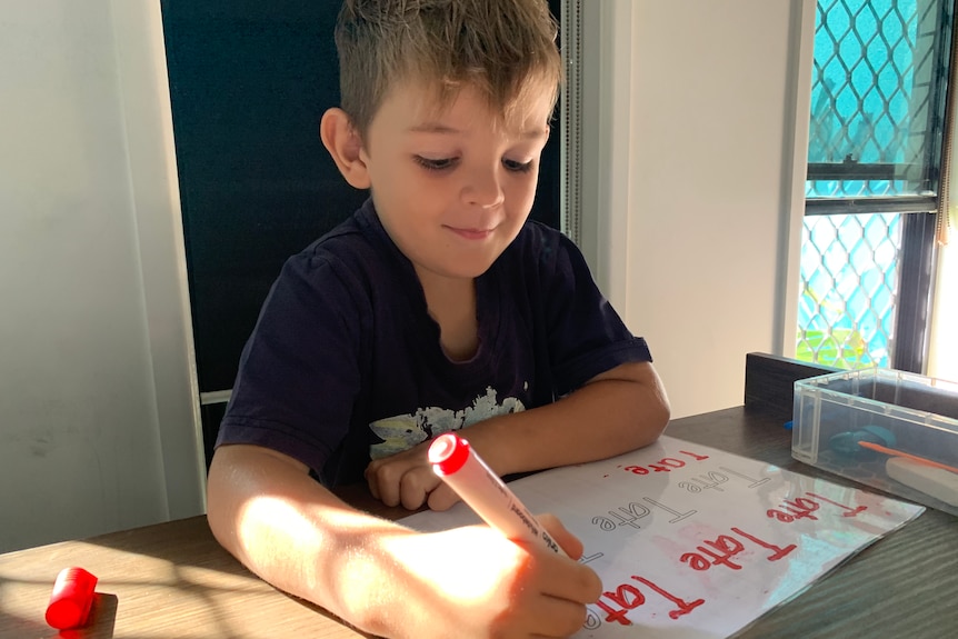 kid sits tracing word on a piece of paper