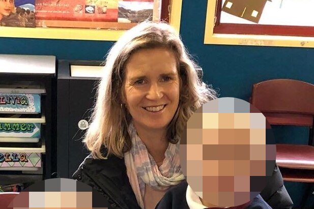 A smiling woman with two children, their faces pixelated