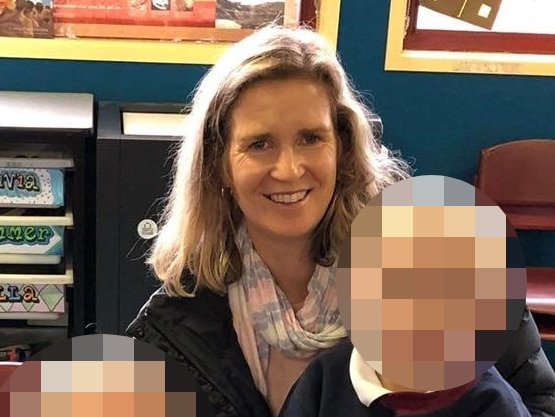 A smiling woman with two children, their faces pixelated