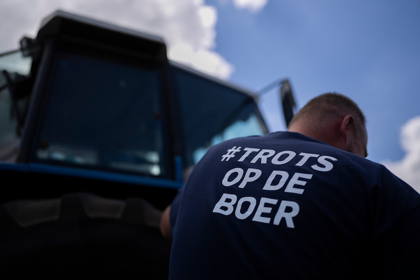 A farmer is pictured in front of a tractor wearing a shirt saying 'Proud of the farmer'.