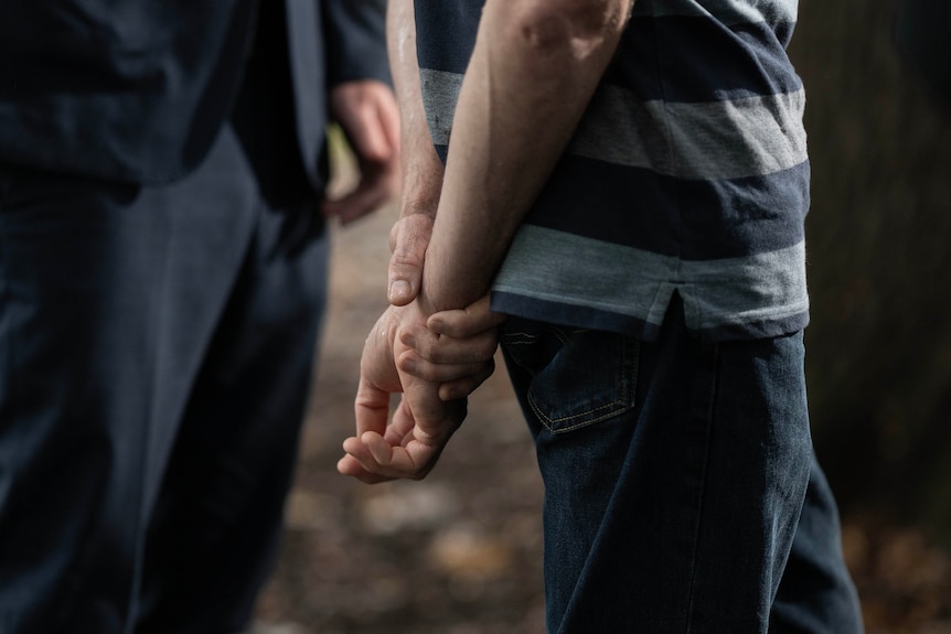 A man holds his hands behind his back.