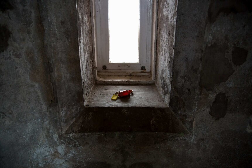 A set of keys rests on the sill of a window inside the Gabo Island lighthouse, the walls a mottled texture.