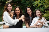 Two women seated with their daughters on their laps. All are smiling
