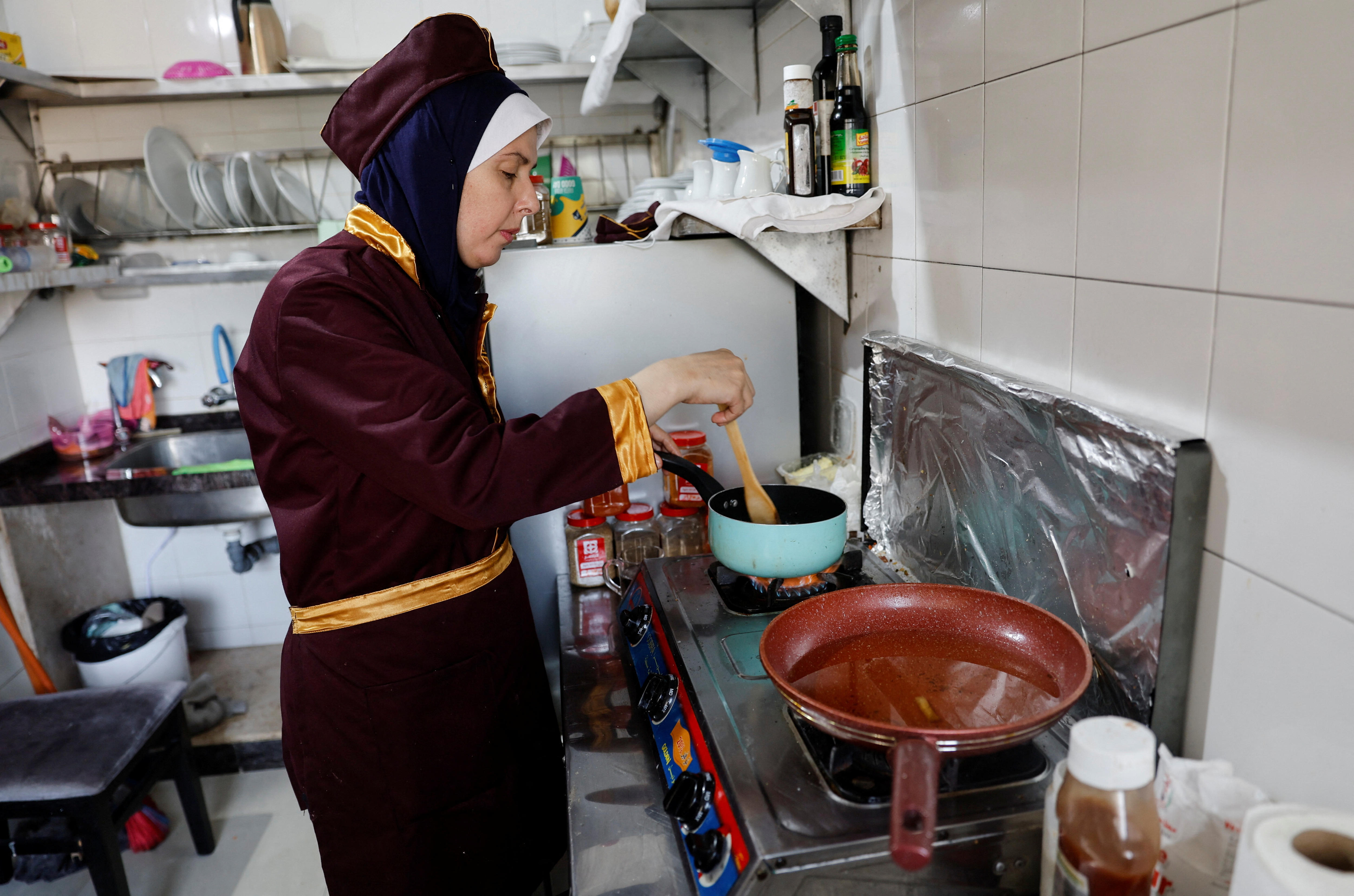A woman in a kitchen stirring a pot on a stove