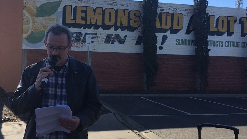 Author Nick Gadd talking into a microphone in front of sign that says 'Lemons add a lot to life'.