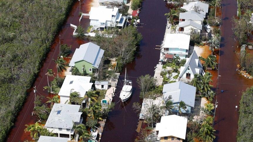 A boat lies secured in a canal between homes and flooded streets.