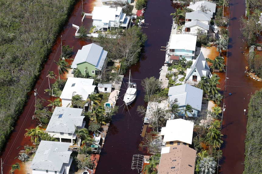 A boat lies secured in a canal between homes and flooded streets.