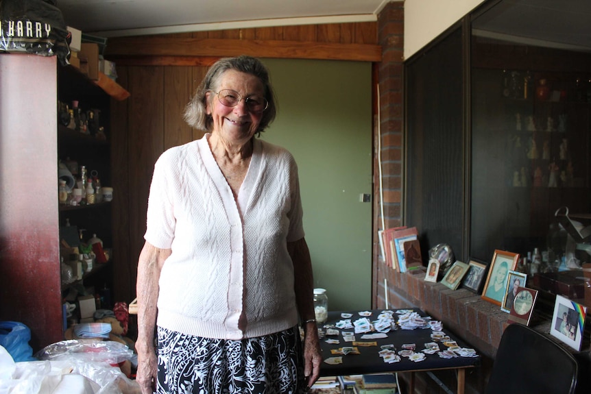 Lyn Saul standing in her stamp room with photo frames and stamp table in the background.