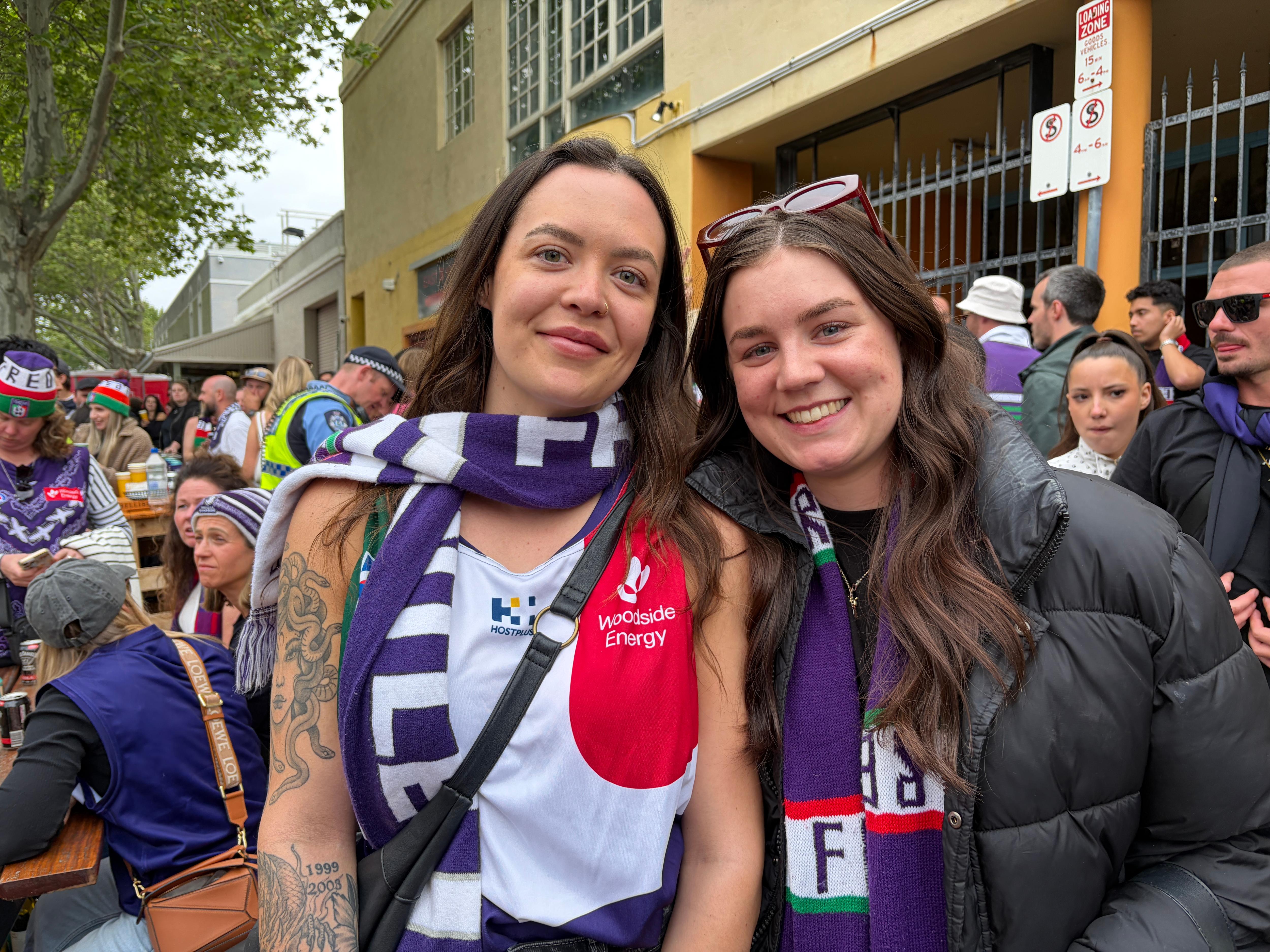 Two woman have a purple scarf on in crowds. 