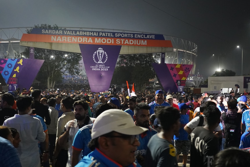 Fans leave the stadium at night near a sign that reads "NARENDRA MODI STADIUM"