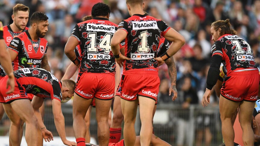 Tyson Frizell lies on the ground concussed as his Dragons teammates surround him.