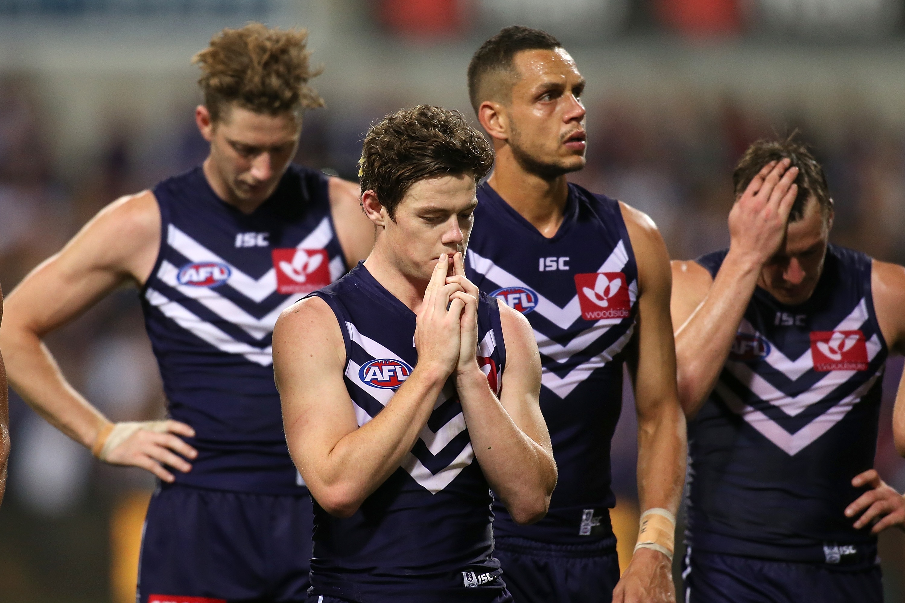 Lachie Neale covers his mouth and walks with teammates