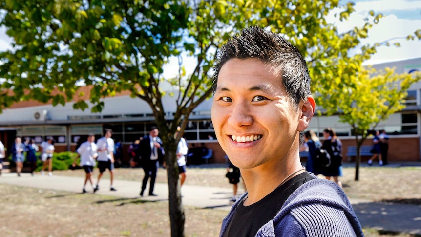 Vincent Shin looks into camera as students walk past at School in background.