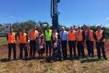 Local, state, and federal politicians stand with traditional owners in front of the drill that performed the sod turning