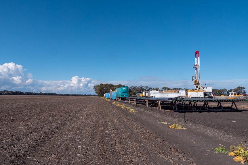 A gas drilling rig next to a bare paddock