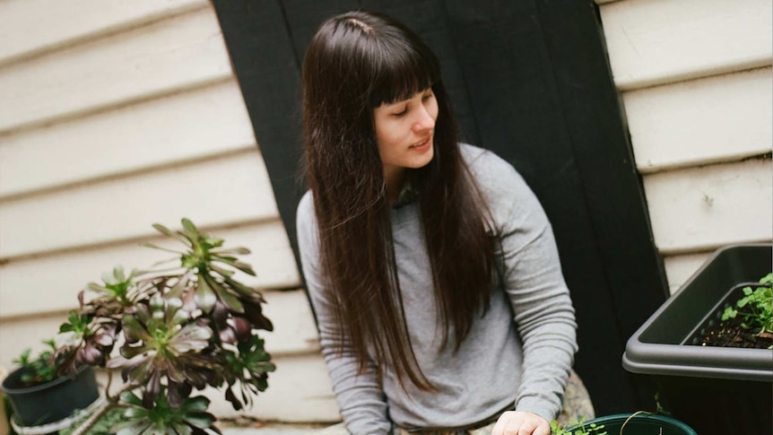 Elizabeth Flux sitting among pot plants