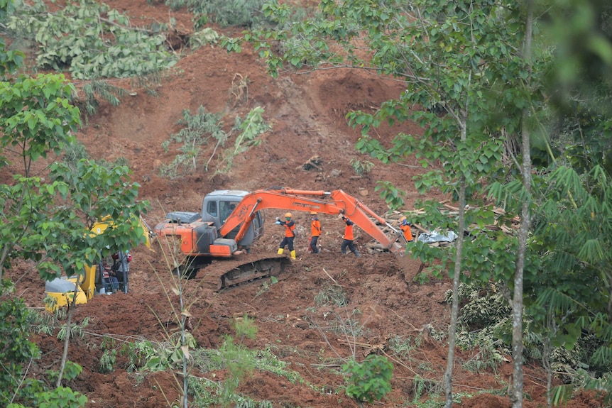 An earthmover and several people work on a hillside of disturbed earth.