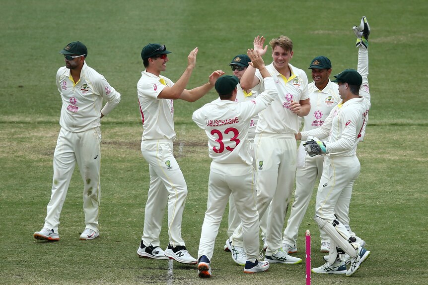 Australian Test cricketers gather around Cameron Green after a wicket against England at the SCG.