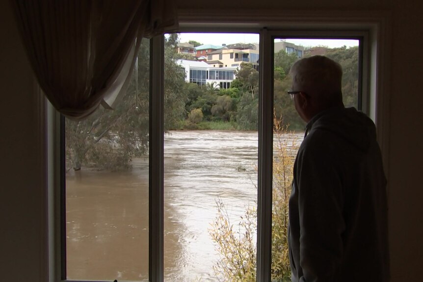 Des stands at his window where the swollen river gushes past.