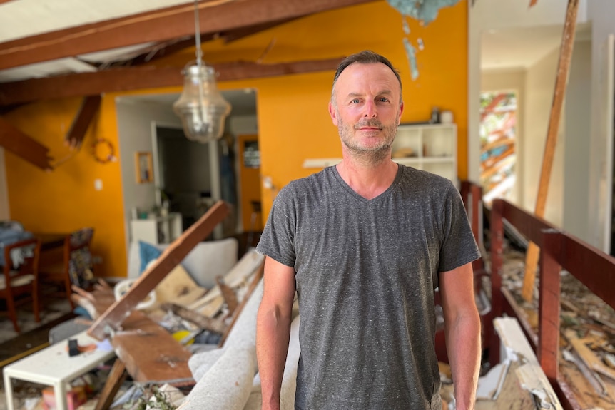 man standing in a storm ravaged home