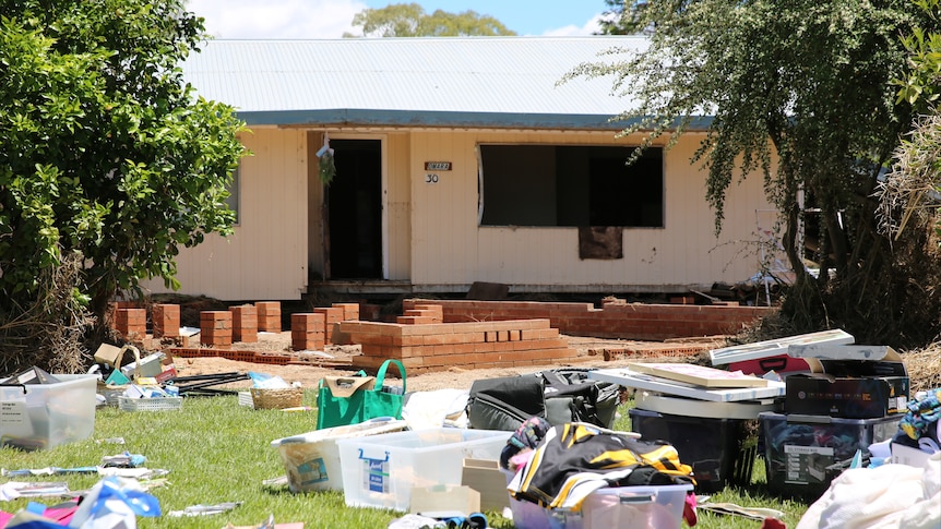 A damaged home with debris strewn across the front yard.