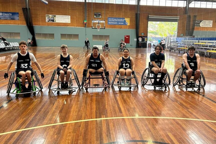 A wheelchair basketball team wearing matching uniforms on an indoor court.