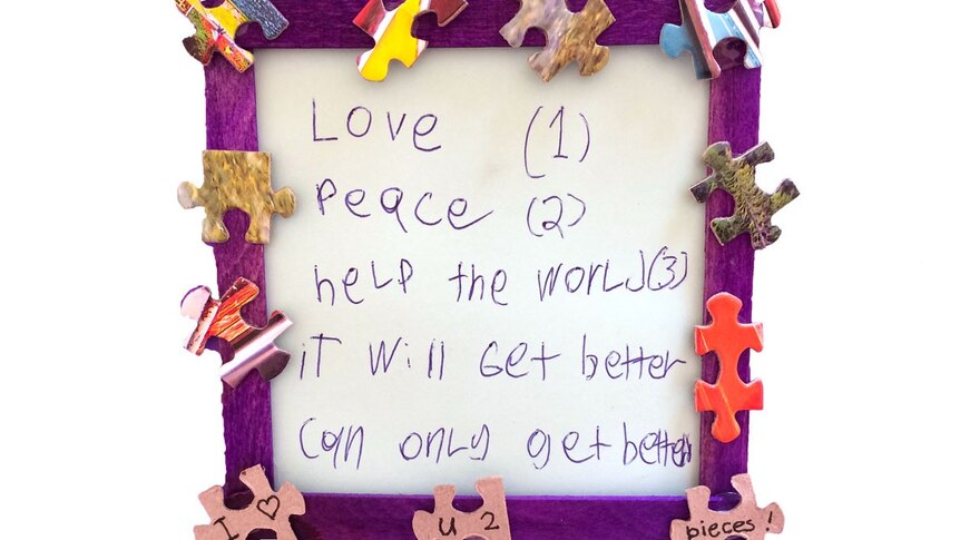A framed note showing a list of wishes (love, peace, help the world) and the phrase 'it will get better, can only get better'.