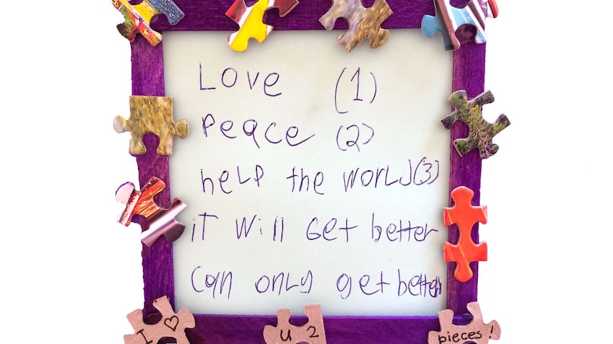 A framed note showing a list of wishes (love, peace, help the world) and the phrase 'it will get better, can only get better'.