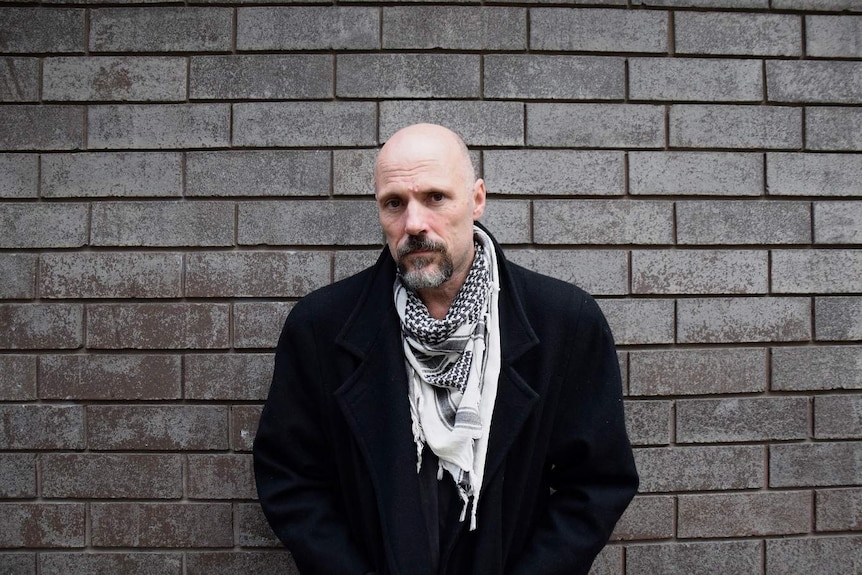 Portrait of Jerry Retford in front of a dark brick wall, he confronted his toxic masculine behaviour.