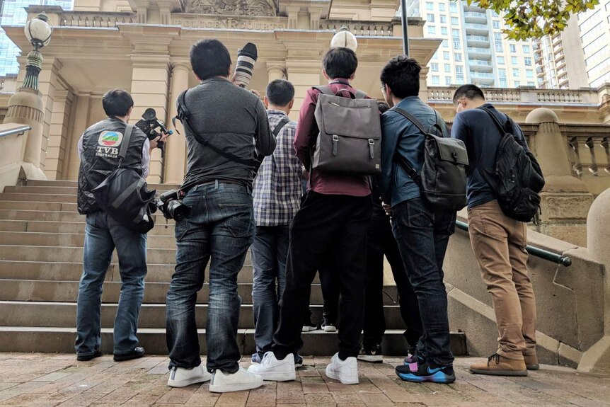 Several people holding cameras with their backs turned.