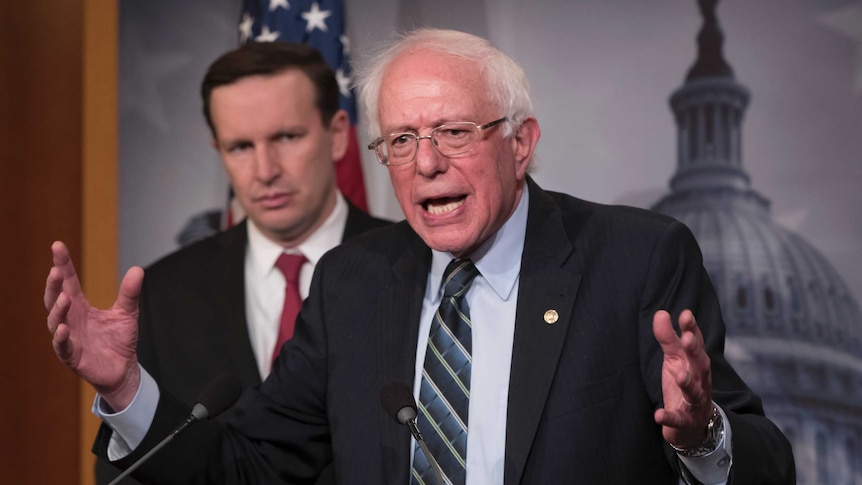 Sen. Bernie Sanders speaks at a press conference, with Sen. Chris Murphy standing behind him